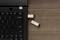 Un ordinateur portable noir avec un clavier USB, dans lequel deux clés USB sont branchées, est posé sur une table en bois.
