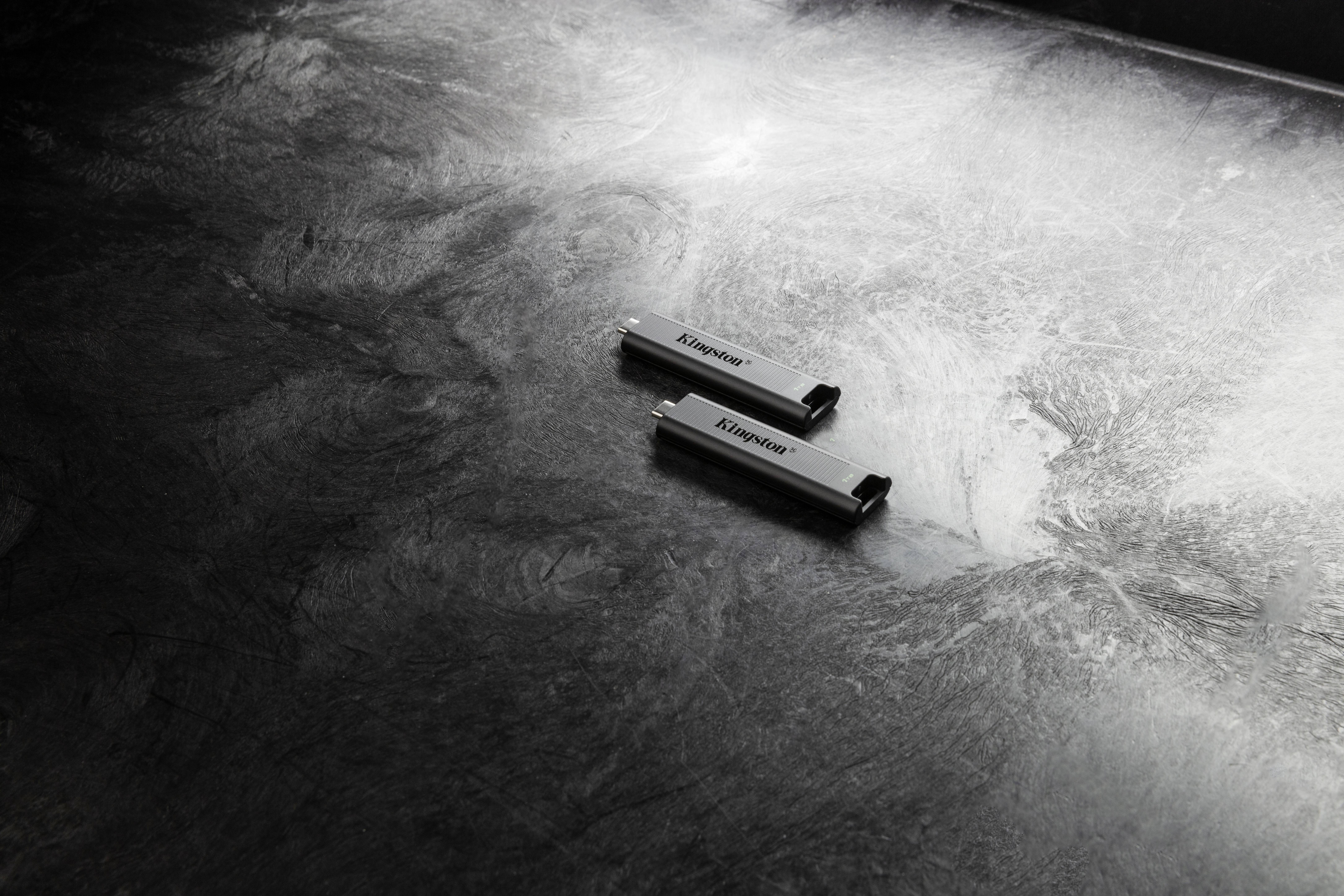 Deux clés USB reposent sur une surface sombre et texturée. Les clés sont identiques et ne portent aucun logo ou étiquette visible.