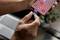 Une personne branche un câble de charge dans un smartphone. L'écran affiche des applications. Un ordinateur portable et une plante sont visibles en arrière-plan.