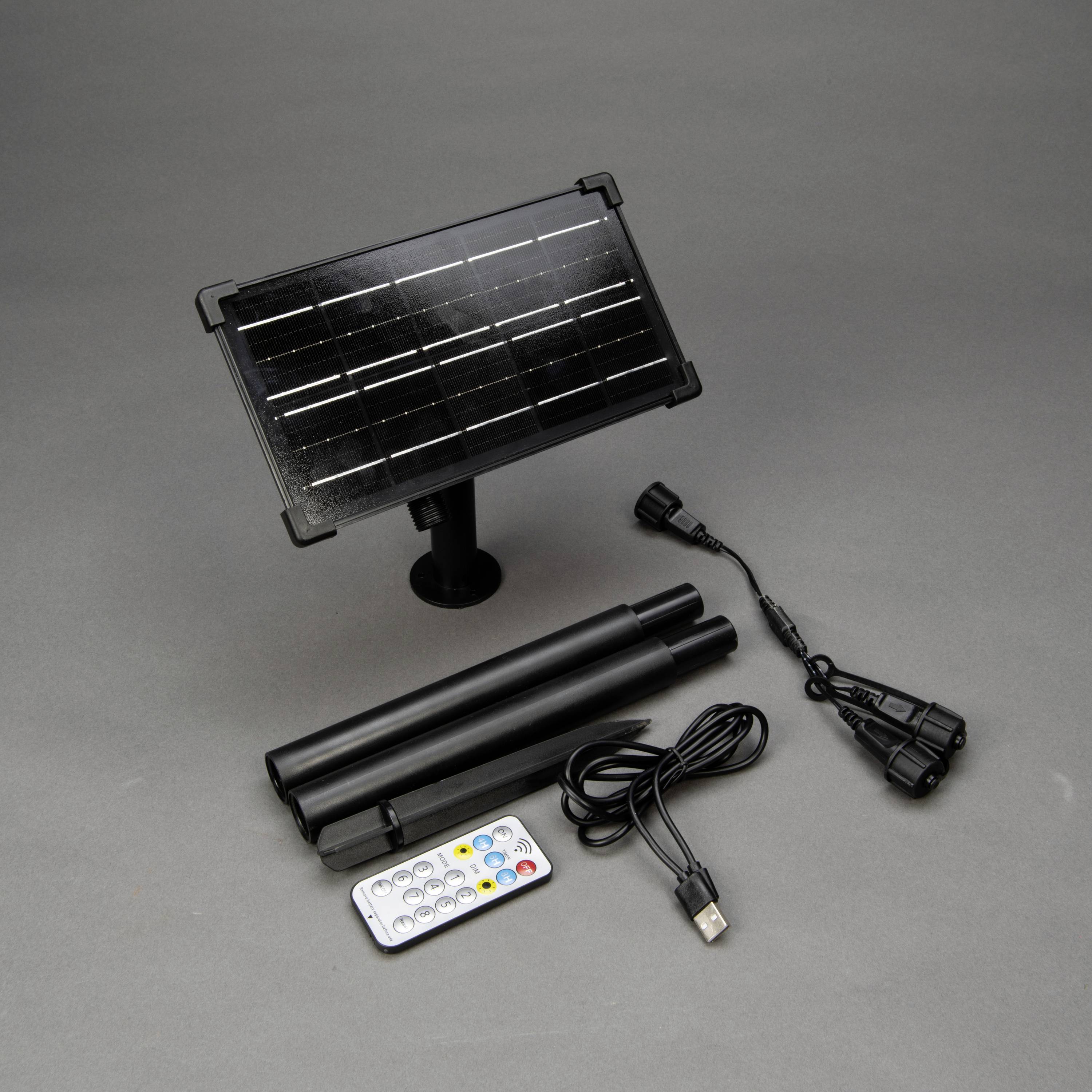 Chargeur solaire avec panneau solaire, deux perches amovibles, câble USB, télécommande et adaptateur sur fond gris.