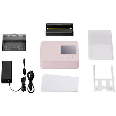 Un imprimante photo rose avec accessoires : bloc d'alimentation, papier, cassettes à papier et ruban encreur. Adapté pour la création immédiate de photos.
