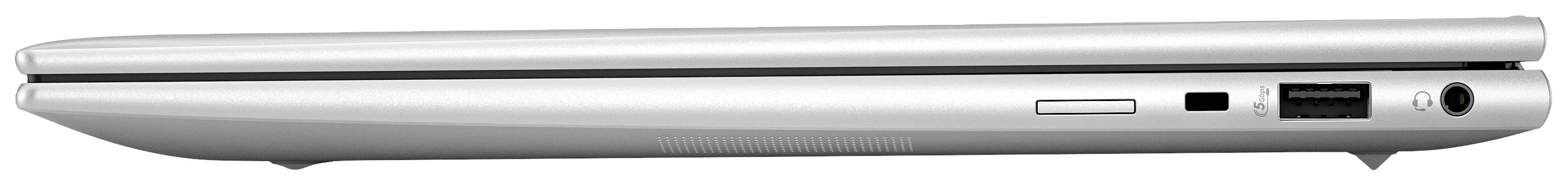 Un ordinateur portable argenté fermé, vu de côté, montrant ses ports et ses fentes de ventilation.