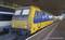 Un train jaune et bleu des chemins de fer néerlandais est à l'arrêt sur un quai dans une gare moderne. Un autre train est visible à gauche.
