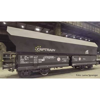 Un wagon de marchandises de l'entreprise Captrain est stationné dans un hangar. Le wagon est noir avec des inscriptions blanches et jaunes.