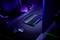 Bureau avec clavier, souris et moniteur de gaming dans un environnement sombre, éclairé par des lumières LED colorées. Un fauteuil de bureau est placé sur la gauche.