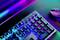 Un clavier et une souris de gaming dans une lumière néon, avec des touches qui s'illuminent dans différentes couleurs. Un bureau sombre est visible en arrière-plan.