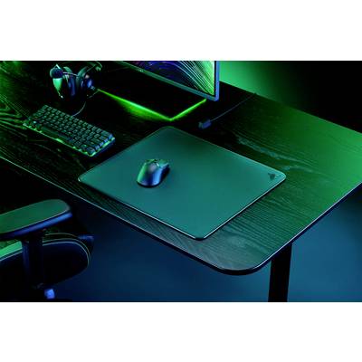 'Bureau d'ordinateur noir avec clavier, souris, tapis de souris et moniteur. Éclairage en lumière verte, configuration de jeu.'