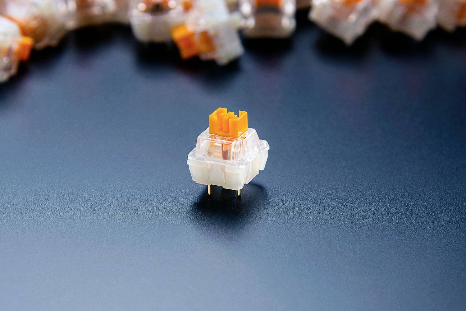 Un interrupteur à touches mécaniques avec un tampon orange est au premier plan, entouré d'autres interrupteurs en arrière-plan.