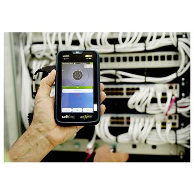 Main tenant une sonde de test réseau portative devant un rack serveur avec de nombreux câbles ethernet connectés et des commutateurs.