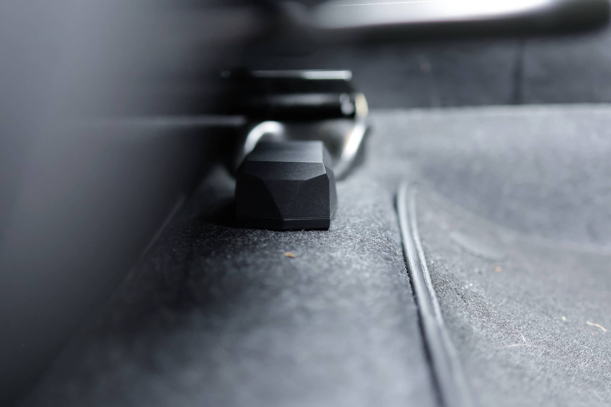 Un bloc noir en plastique est posé sur un tapis gris. Le bloc est placé au centre de l'image et encadré par un cadre métallique.