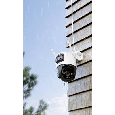 Une caméra de surveillance est montée sur le mur extérieur d'un bâtiment. Il pleut, et des gouttes d'eau tambourinent sur la caméra.