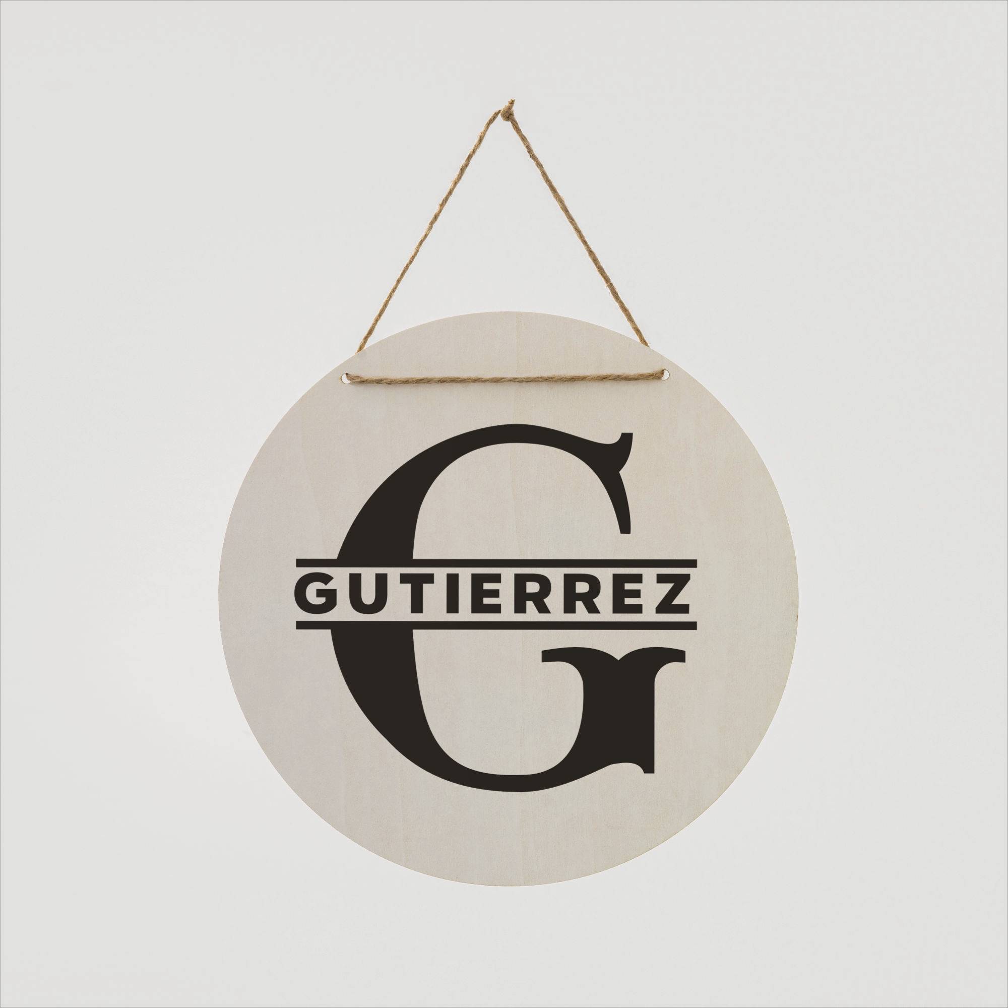 Panneau rond en bois portant le nom 'GUTIERREZ' avec un grand 'G', suspendu par une corde.