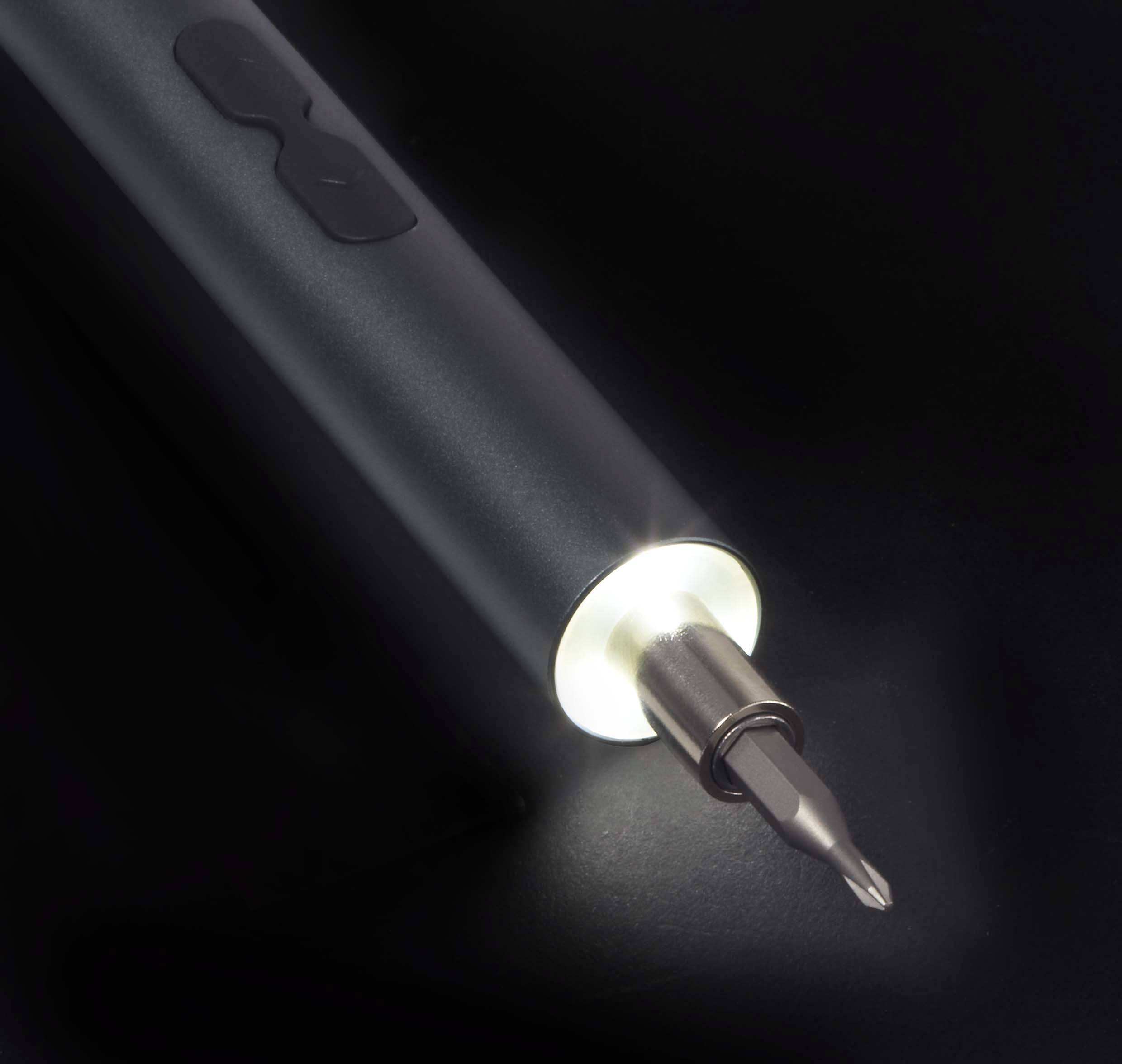 Un tournevis éclairé sur un fond sombre, avec une lumière LED vive à son extrémité, rendant visible l'embout de la vis.