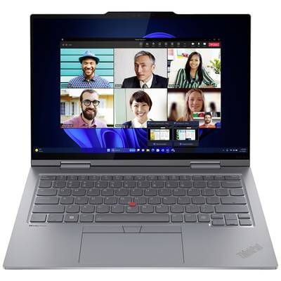 Un ordinateur portable affiche un appel vidéo avec six personnes à l'écran. Tous les participants sourient. La barre des tâches avec des applications ouvertes est visible.