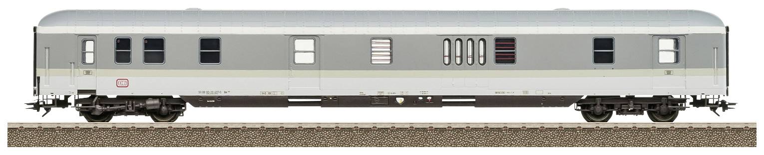Un wagon d'argent stationne sur une voie ferrée. Le wagon possède plusieurs fenêtres et portes.
