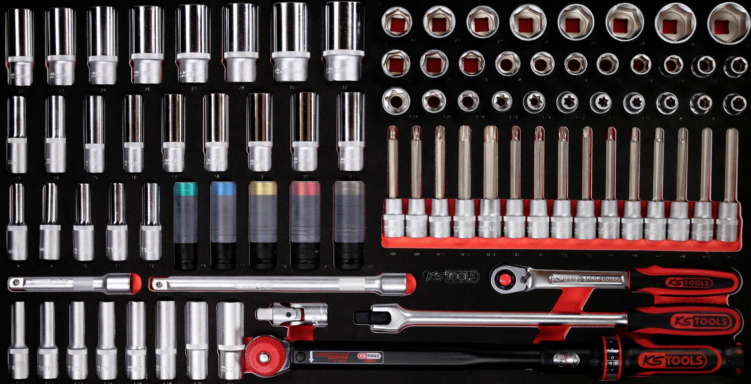 Un ensemble d'outils manuels, comprenant des clés à cliquet de différentes tailles, des clés codées par couleur et des outils de vissage, disposés sur un fond noir.