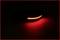 Une bande LED rouge vive dans un environnement sombre, formant une ligne courbe. Elle émet une lumière rouge intense.