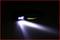 Une lampe frontale allumée repose sur un fond sombre, projetant un faisceau lumineux puissant vers l'avant, la lumière étant blanche et vive.