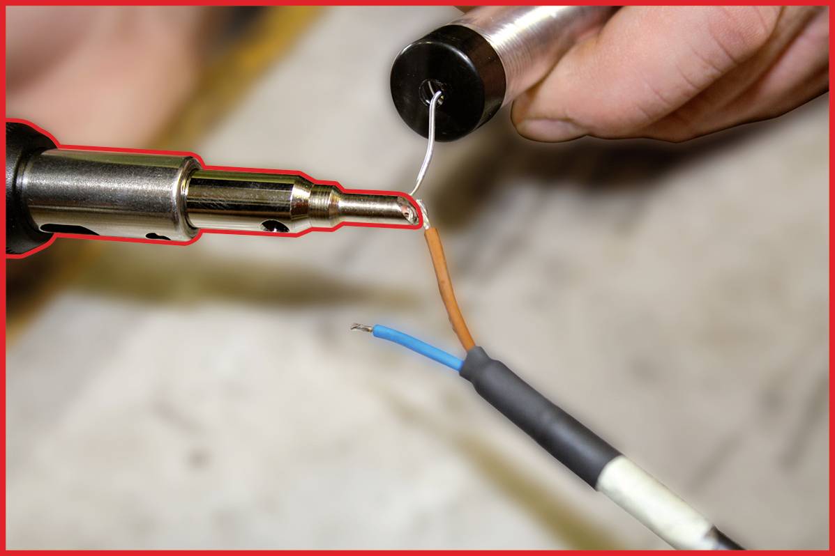 'Deux fils sont reliés à l'aide d'un fer à souder. Une main maintient les fils, tandis que l'autre guide le fer.'