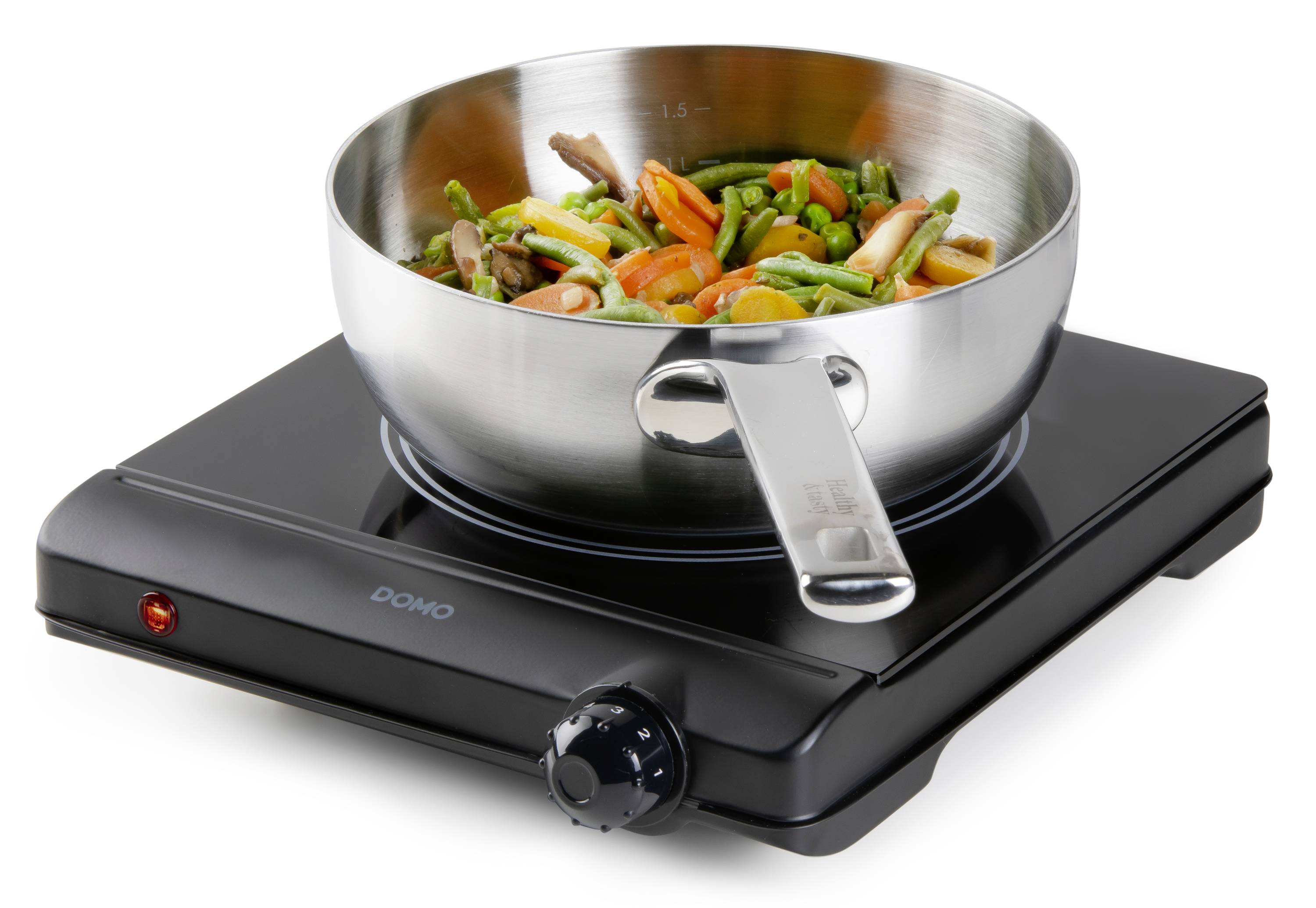 Une plaque de cuisson électrique avec une casserole contenant une poêle à légumes. La casserole présente des livres, dont des carottes et des asperges.