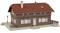 Une petite maquette d'une maison en briques avec un toit rouge et des volets blancs. Des cheminées et une entrée avec un escalier sont visibles.