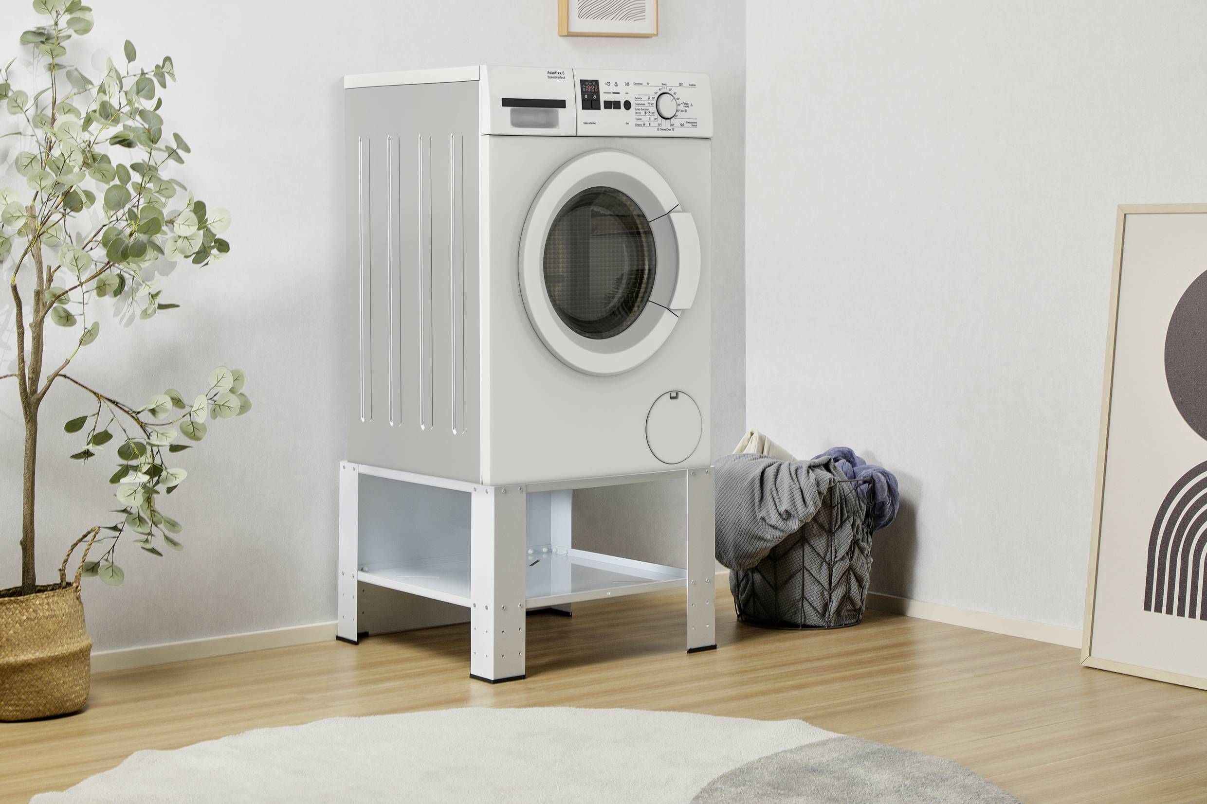 Une machine à laver blanche est placée sur un socle dans une pièce lumineuse. À gauche se trouve une plante, à côté un panier de linge.