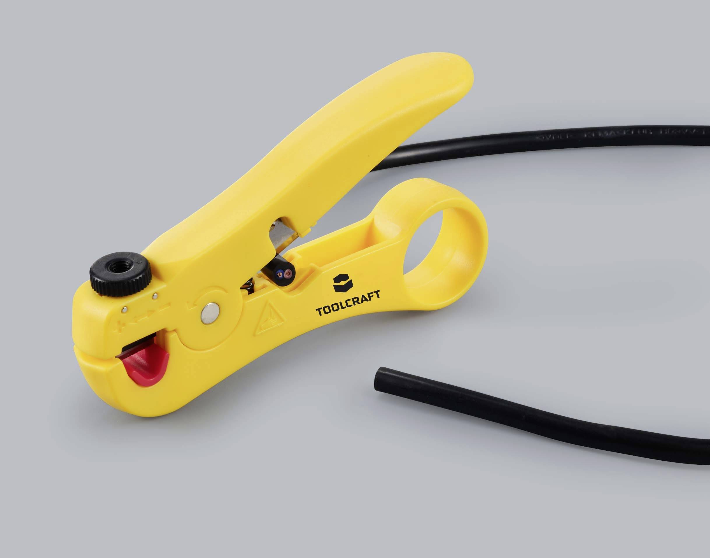 Un outil de dénudage jaune 'Toolcraft' est posé sur un fond gris à côté d'un morceau de câble noir.