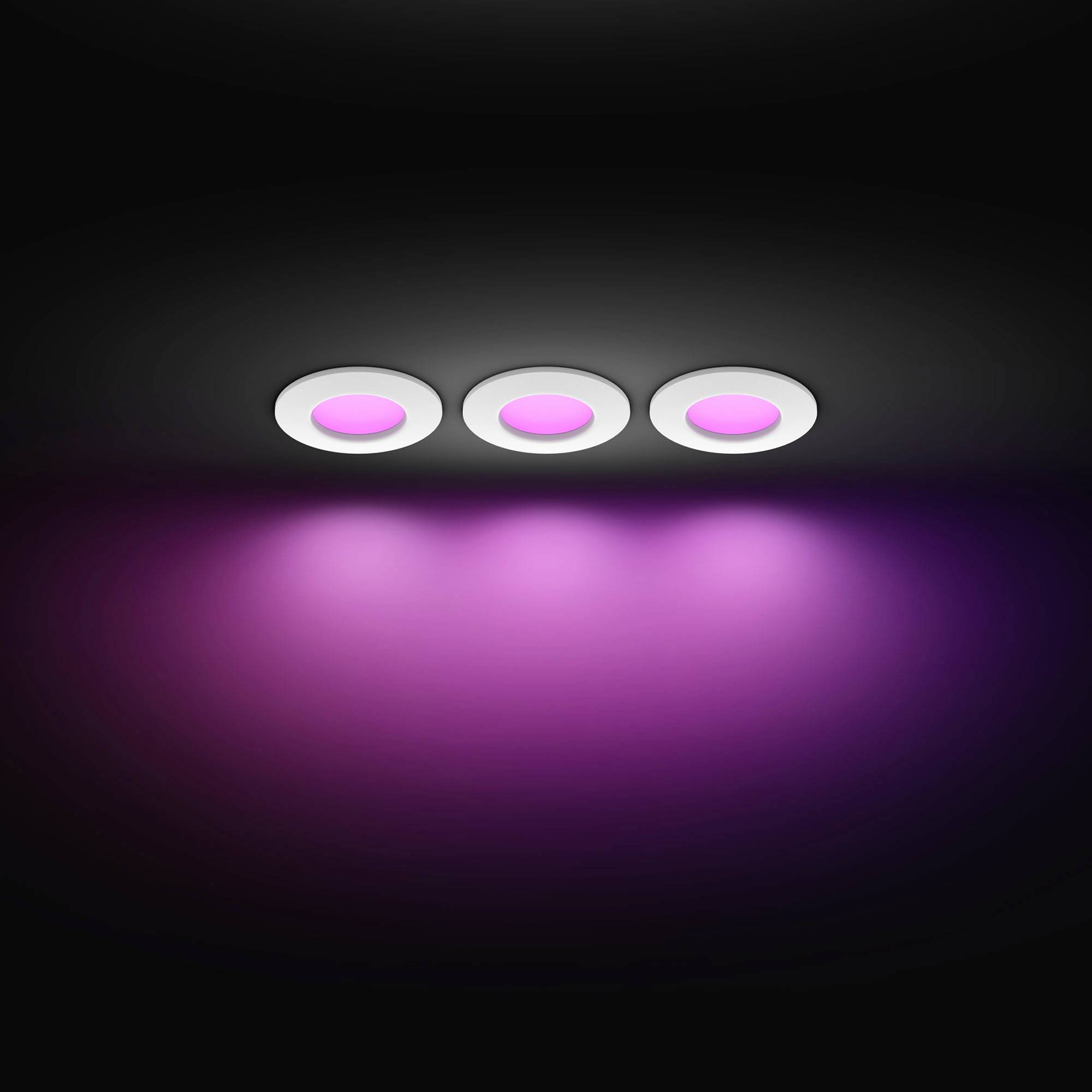 Trois luminaires circulaires au plafond émettent une lumière violet vif, créant une lueur douce sur la surface en dessous.
