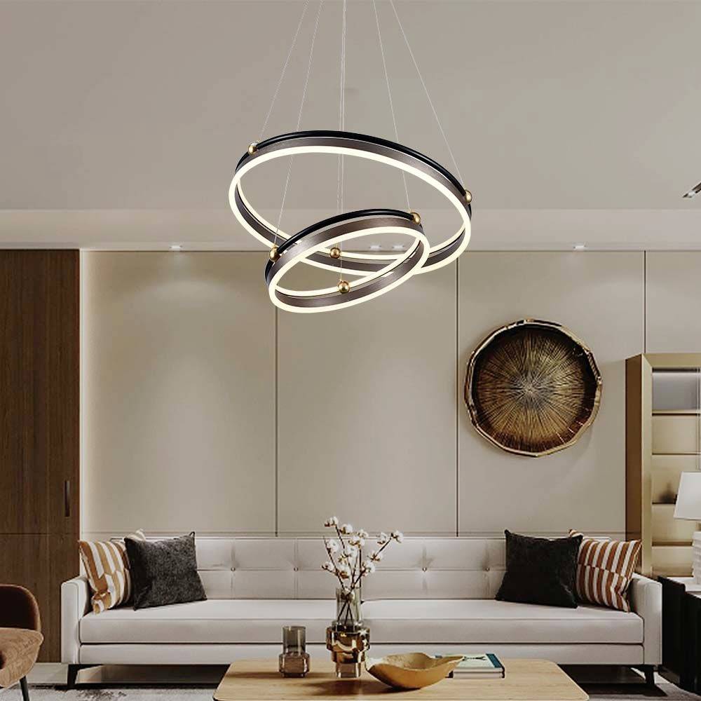 Un salon moderne avec un canapé blanc, des coussins décoratifs, une table basse ronde et une lampe suspendue en forme d'anneau.