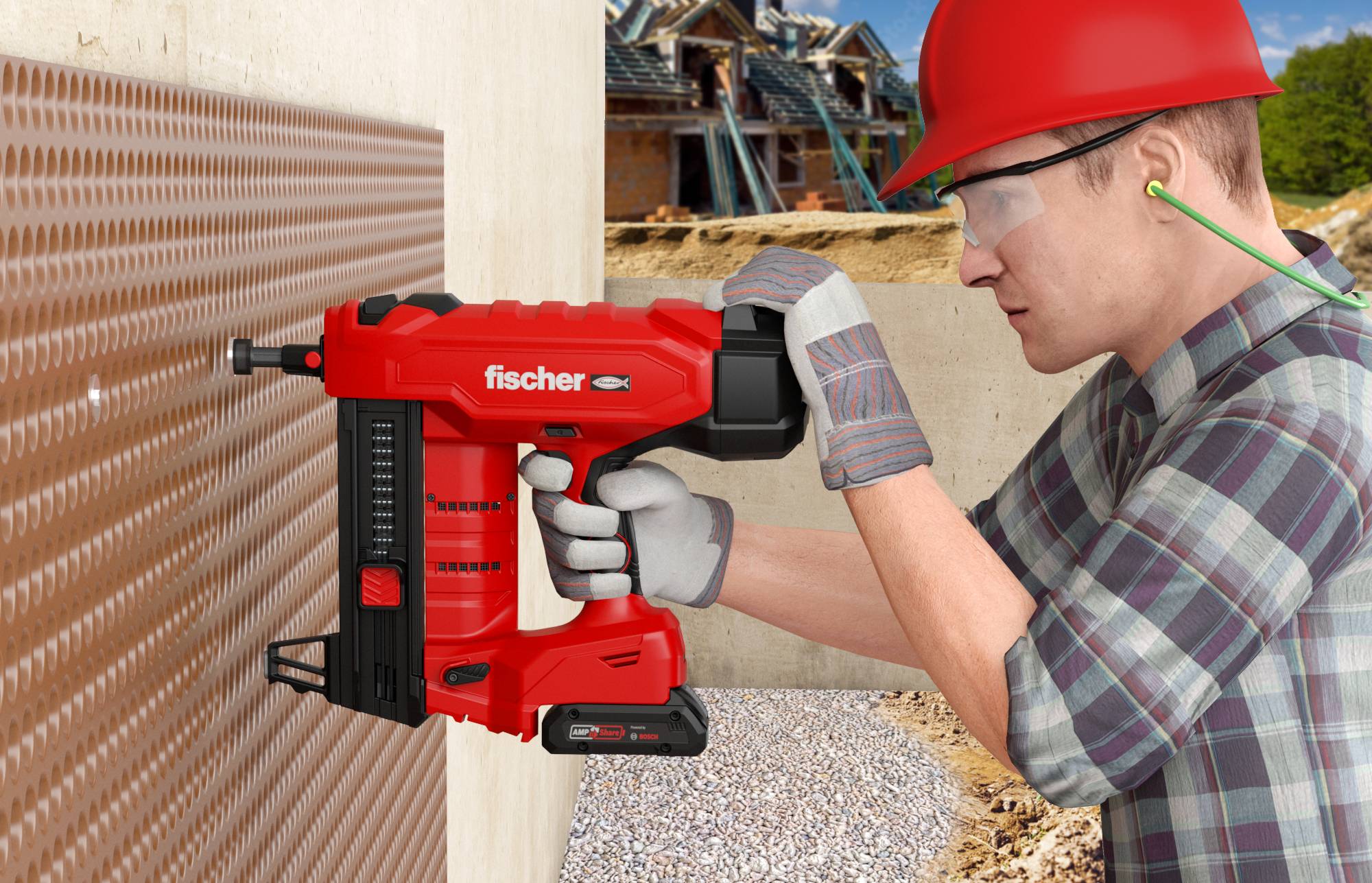 Un ouvrier du bâtiment portant un casque de protection et des lunettes de sécurité utilise un cloueur pneumatique Fischer rouge pour fixer l'isolation à un mur sur un chantier de construction.