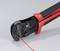 Une pince à sertir, principalement noire avec des poignées rouges, tient un câble rouge, prête à sertir. Adaptée aux travaux électriques.