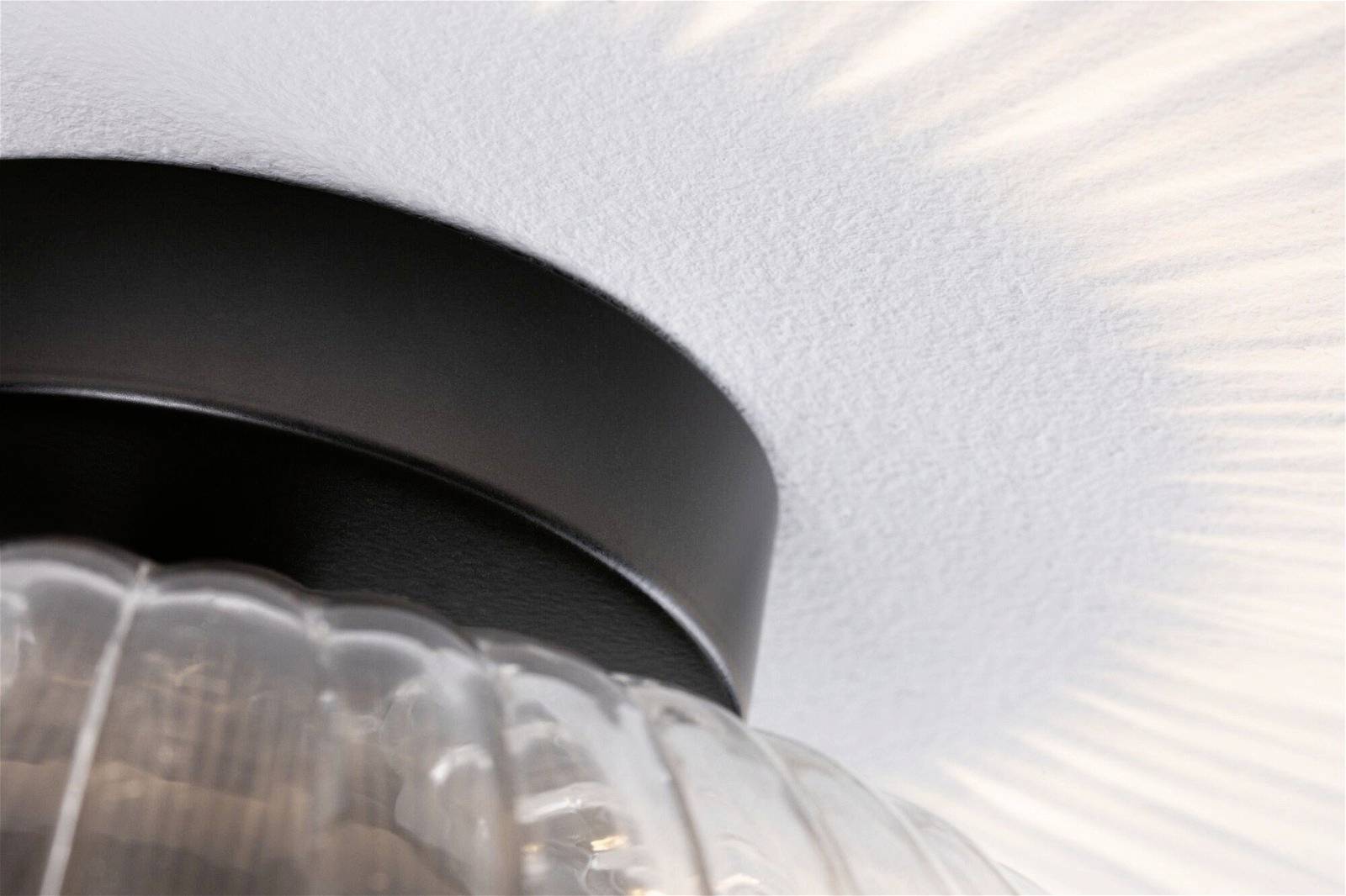 Lampe de plafond avec un effet lumineux circulaire sur une surface blanche.