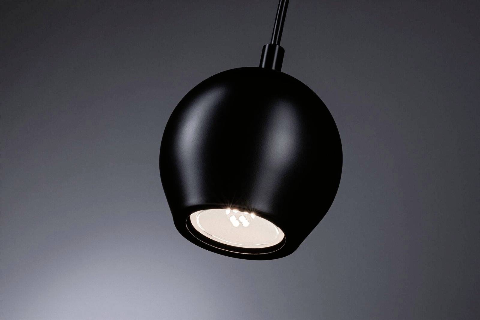 Un luminaire suspendu moderne noir avec un abat-jour rond, éclairant vers le bas et créant une lumière douce.