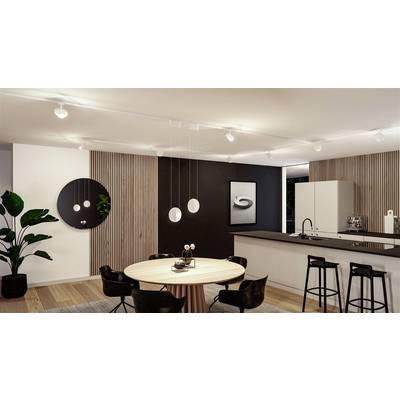 Espace moderne de cuisine et de salle à manger avec une table ronde, des chaises noires, des lampes suspendues, des plantes et une œuvre d'art noir et blanc au mur.