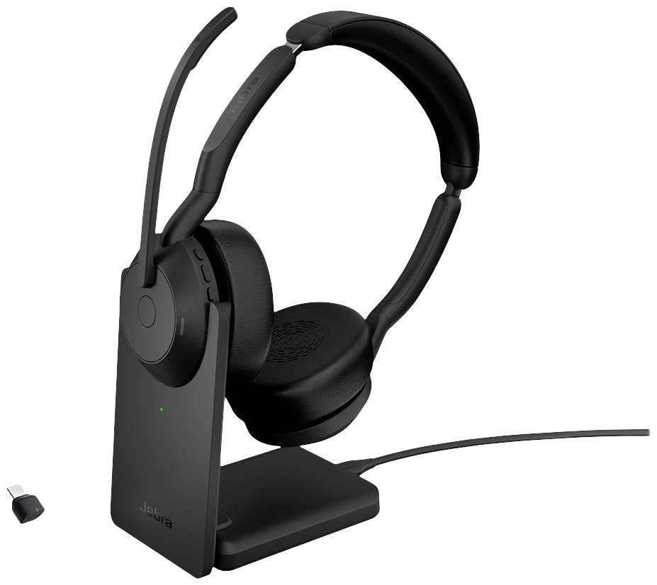 Casque sans fil avec perche micro et coussinets d'oreille sur une station de charge, à côté d'un adaptateur USB. Idéal pour la communication audio.