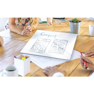 Un groupe de personnes planifie une stratégie de contenu, discutant autour d'une table avec des croquis de maquettes de sites web.