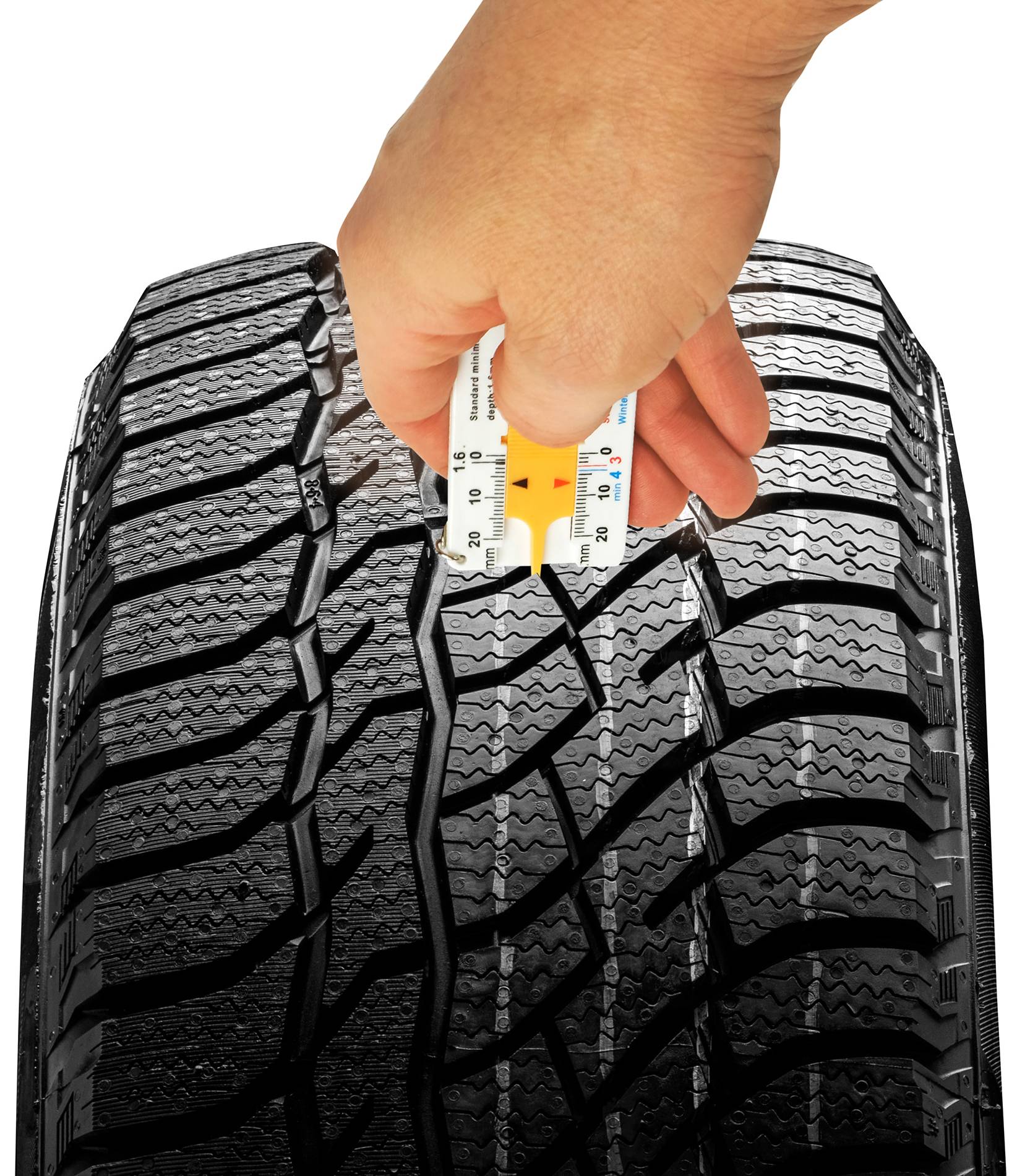 Une main mesure la profondeur du profil d'un pneu de voiture à l'aide d'un outil spécial afin de vérifier son aptitude à la circulation.