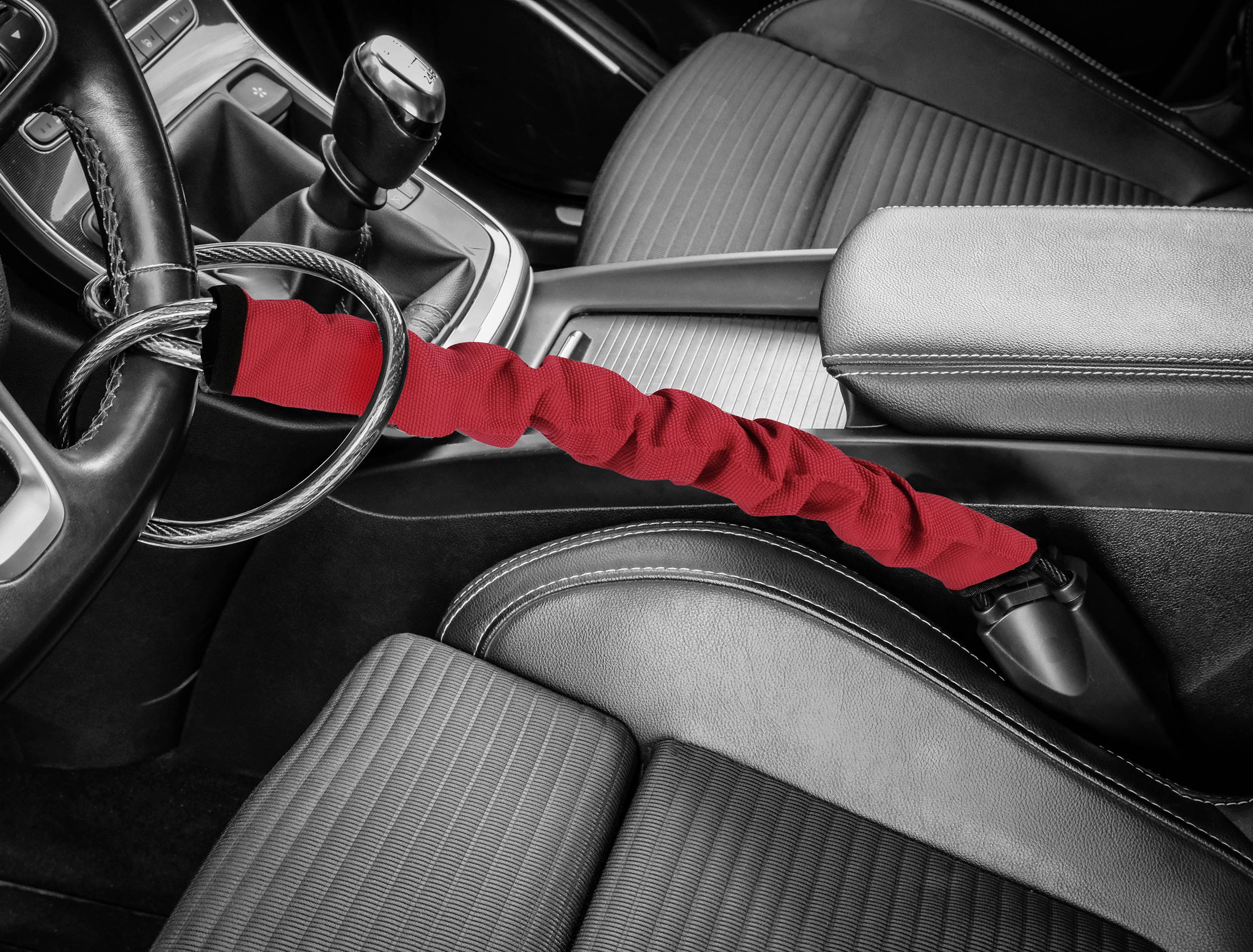 Une clé de voiture avec une protection rouge est fixée à un câble d'acier sur le volant d'une voiture afin de prévenir le vol.