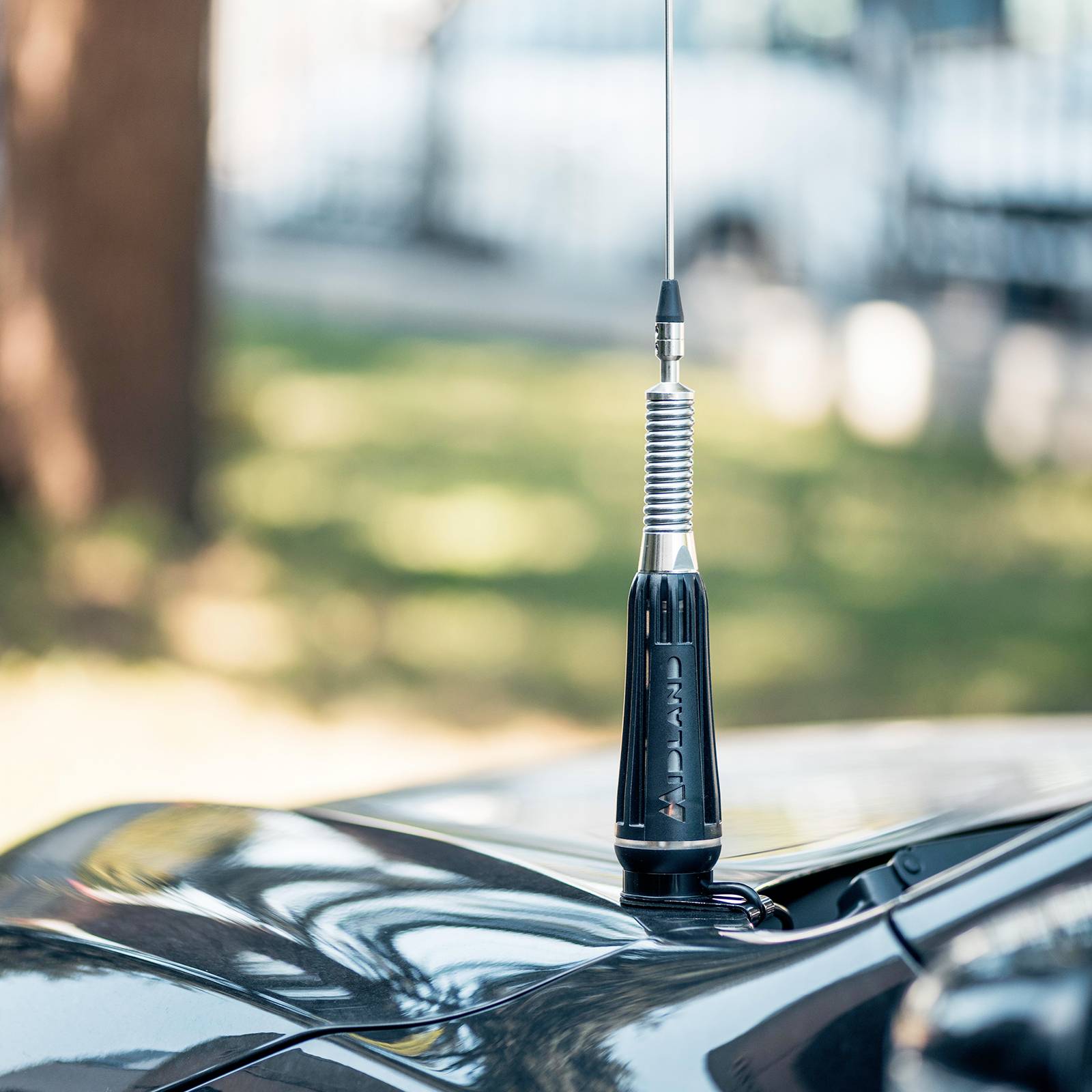 Antenne de voiture sur un toit de véhicule, avec un arrière-plan flou extérieur.