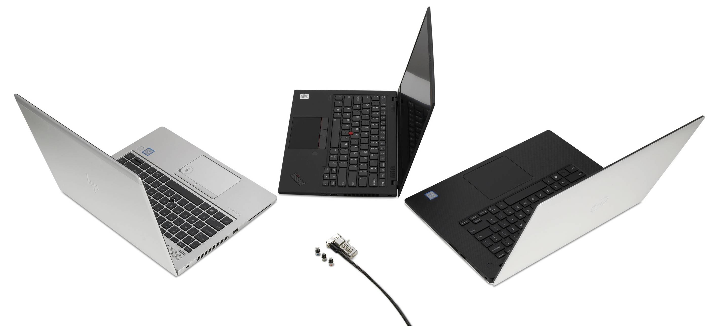 'Trois ordinateurs portables ouverts de différentes couleurs à côté d'un câble adaptateur avec plusieurs ports sur un fond blanc.'