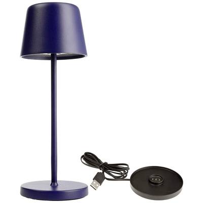 Lampe de table bleue avec socle rond et abat-jour étroit, à côté de laquelle se trouve une station de charge sans fil avec câble USB.