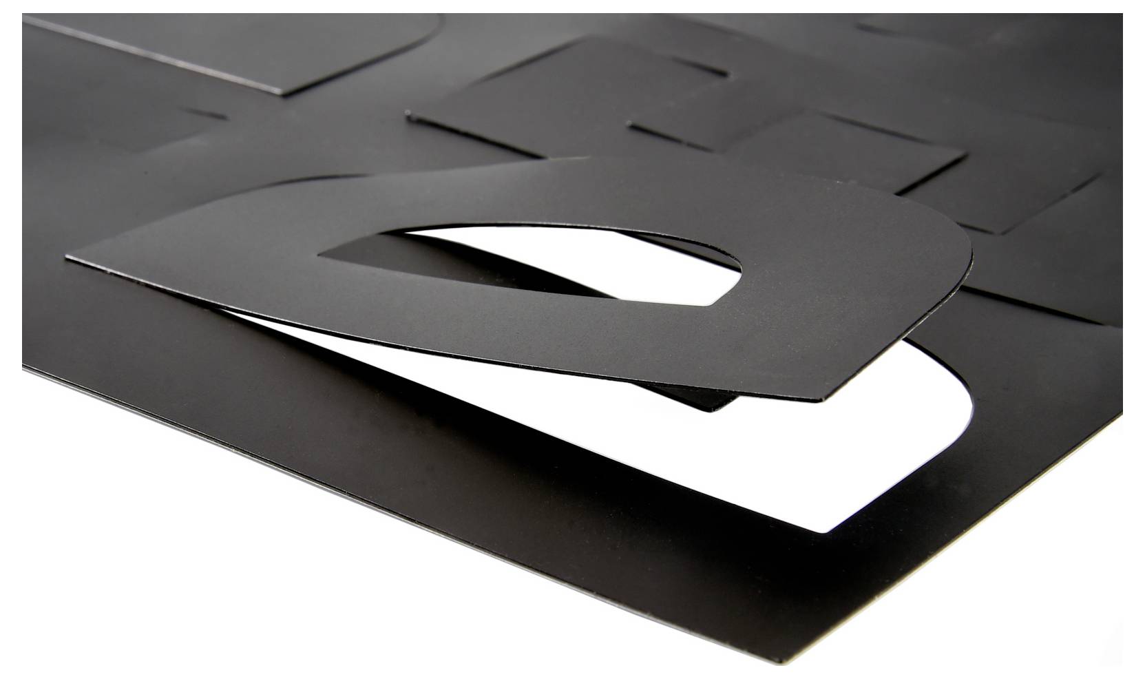 Lettres découpées noires empilées formant un grand « d » minuscule sur une feuille blanche, vues de près sur fond sombre.