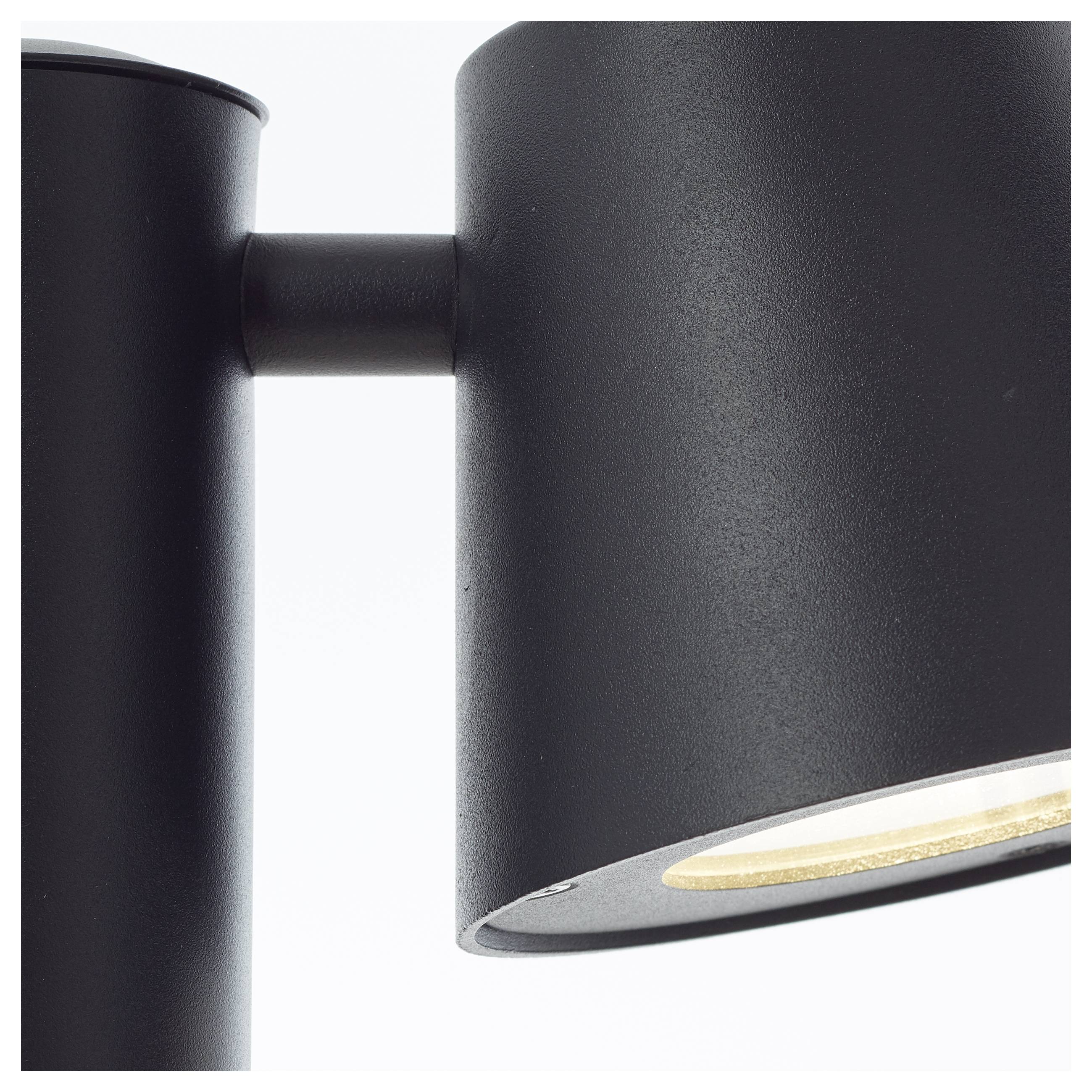 Un applique murale noir avec un abat-jour cylindrique, orienté vers la droite, sur un fond blanc.
