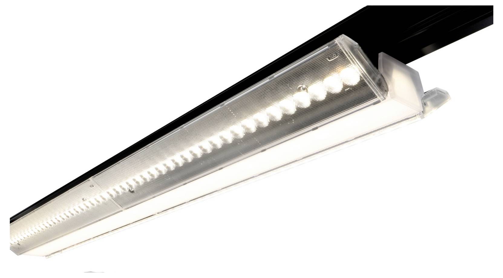 Un long luminaire LED linéaire monté sur une surface noire, vu de dessous selon un angle.