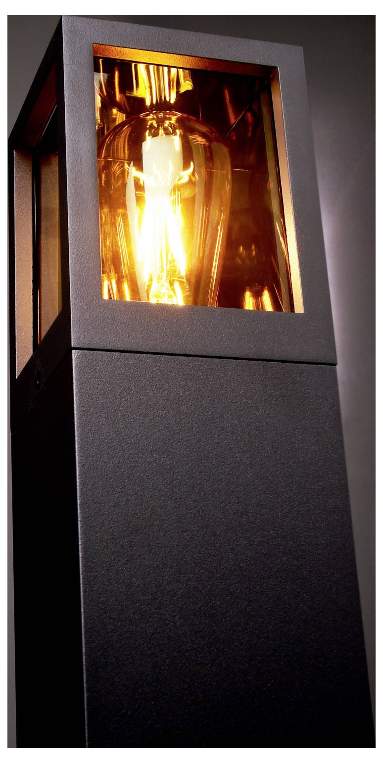 Gros plan d'un lampadaire d'extérieur noir dont la lumière chaude brille à travers une fenêtre carrée en verre.
