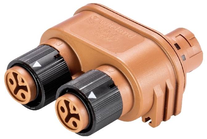 Un connecteur électrique orange-brun avec deux bornes noires et des symboles ronds distinctifs sur la face avant.