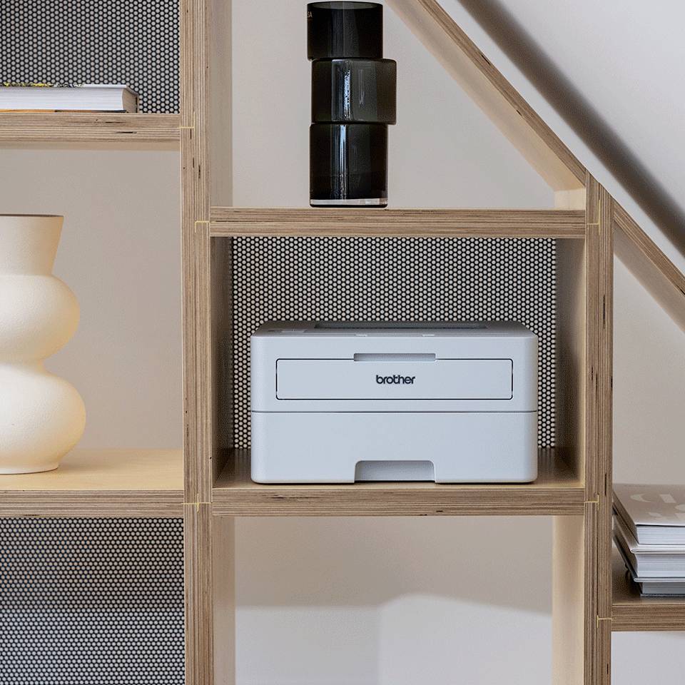 Une imprimante est placée sur une étagère, entourée d'objets décoratifs tels que des vases.