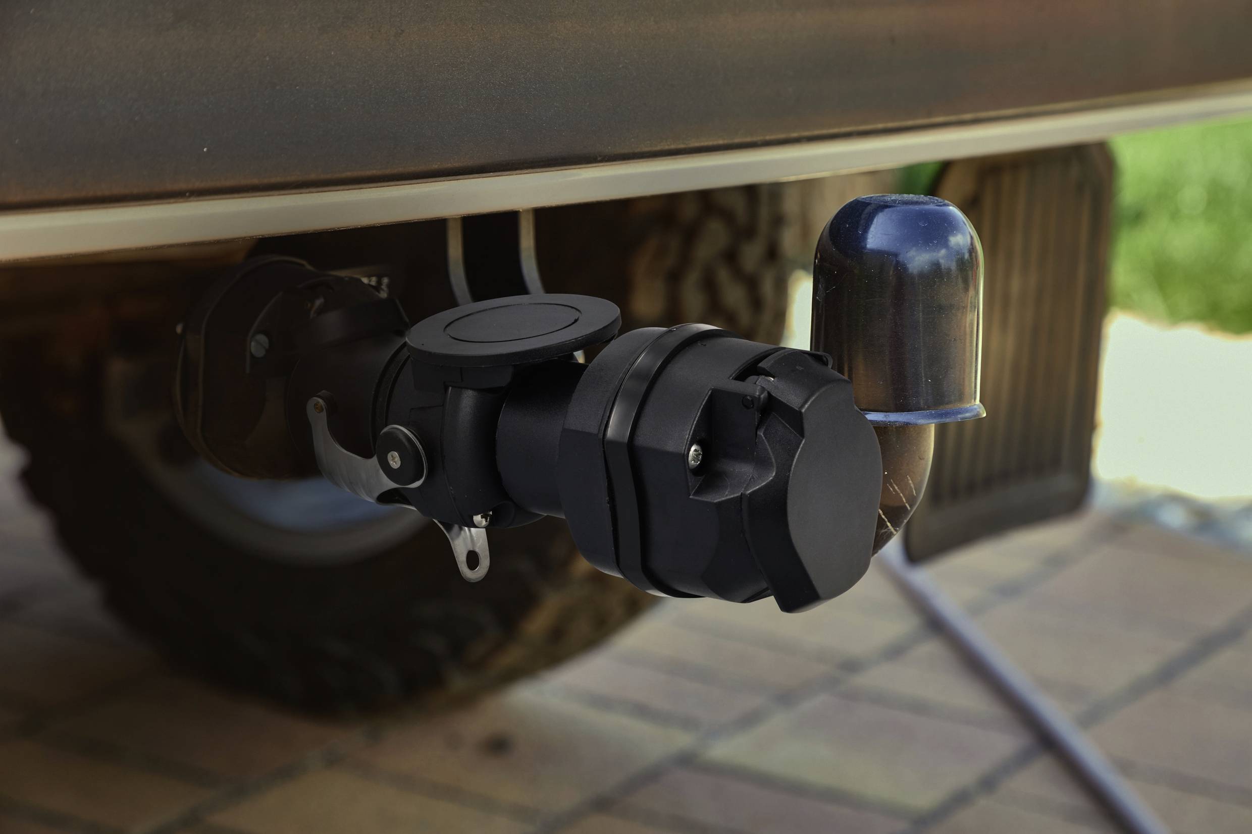 Un pot d'échappement automobile avec un volet tordu et courbé à son extrémité, stationné dans une allée.