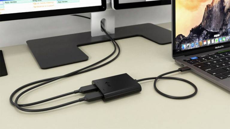 Un ordinateur portable connecté à un hub USB, relié à deux écrans. Les moniteurs affichent différentes applications.