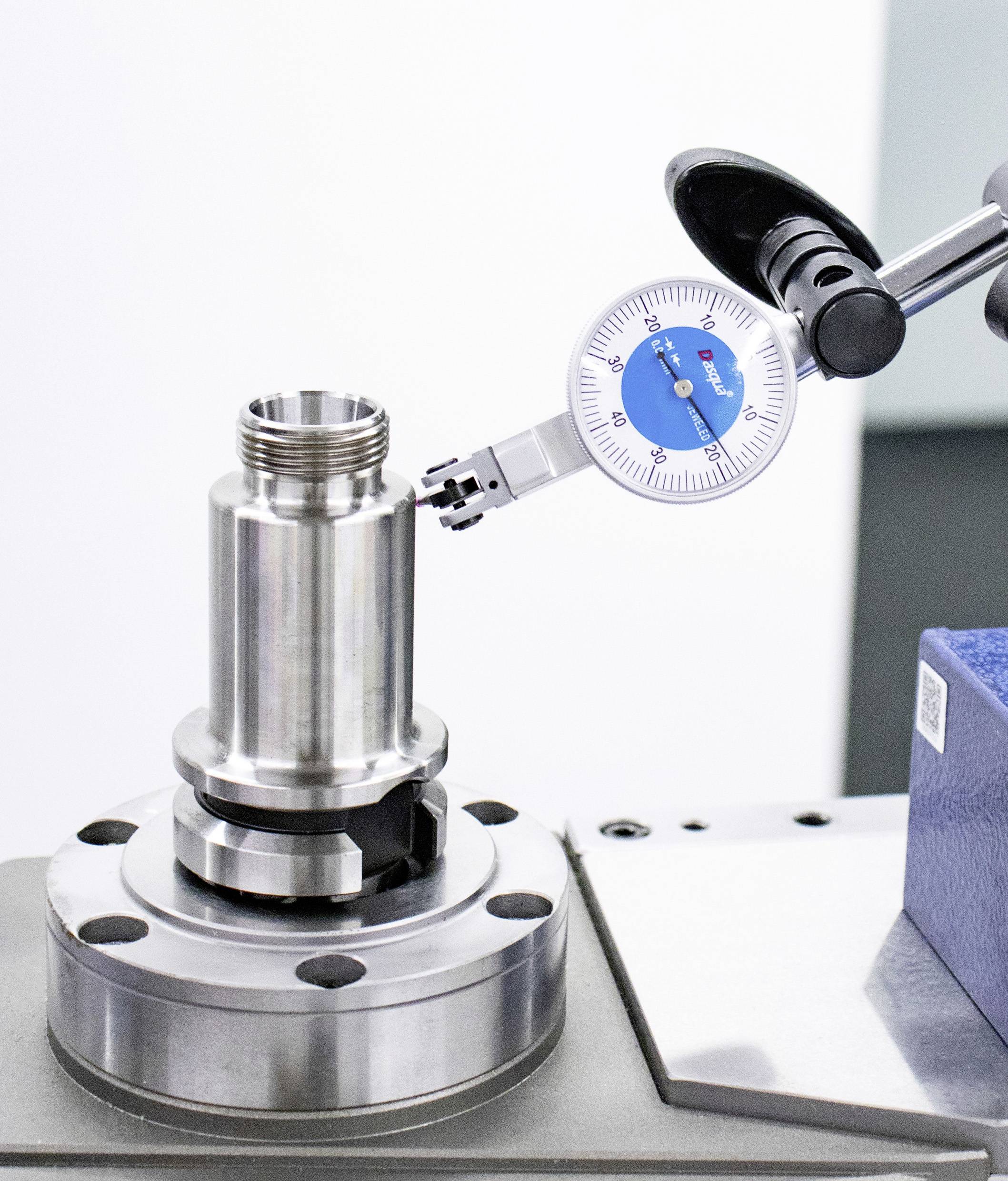 Un instrument de mesure détermine le diamètre d'un cylindre métallique sur un tour. Il illustre la précision de la fabrication industrielle.